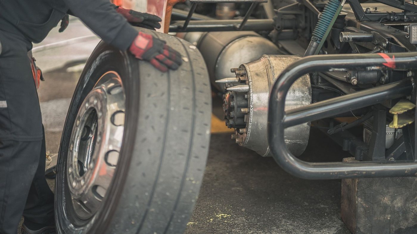 Licensed stock photograph: a heavy wheel and tire being lifted onto an axle.